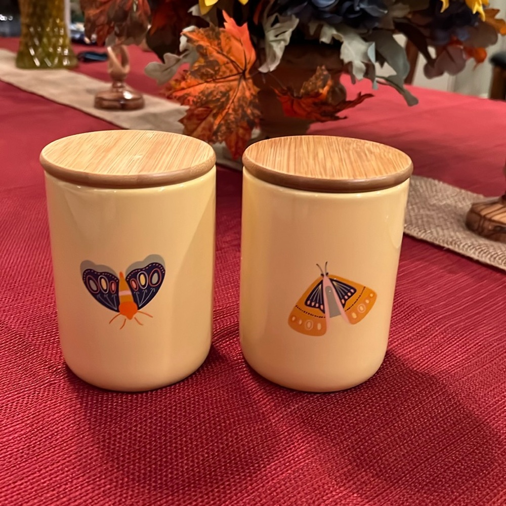 Set of two mini ceramic canisters with wooden lids and two matching tea towels.